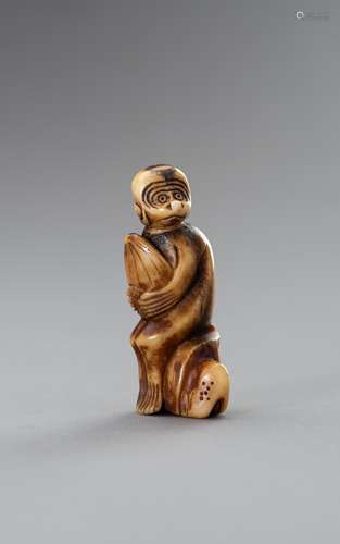 A STAG ANTLER NETSUKE OF A MONKEY HOLDING A PEACH