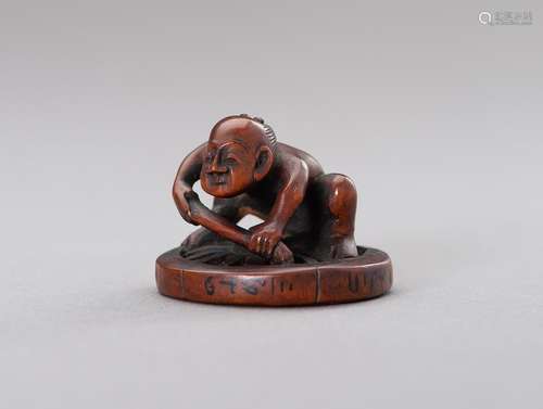 HOKEI: A BOXWOOD NETSUKE OF A MAN FIXING A WHEEL