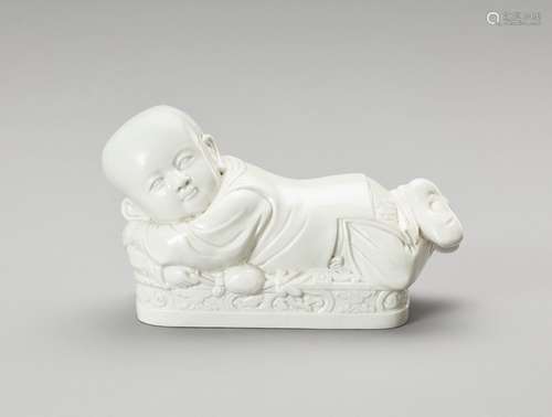 † A WHITE GLAZED DEHUA PORCELAIN 'BOY' PILLOW, EAR...