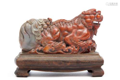 A Chinese shoushan soapstone dragon with bag of money on woo...