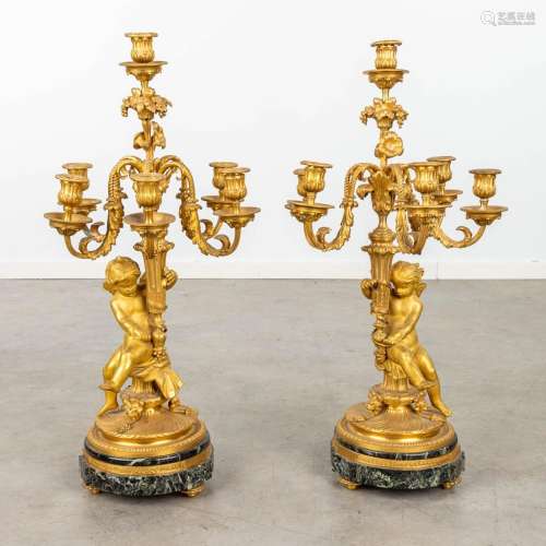 A pair of candelabra made of gilt bronze on a marble stand a...