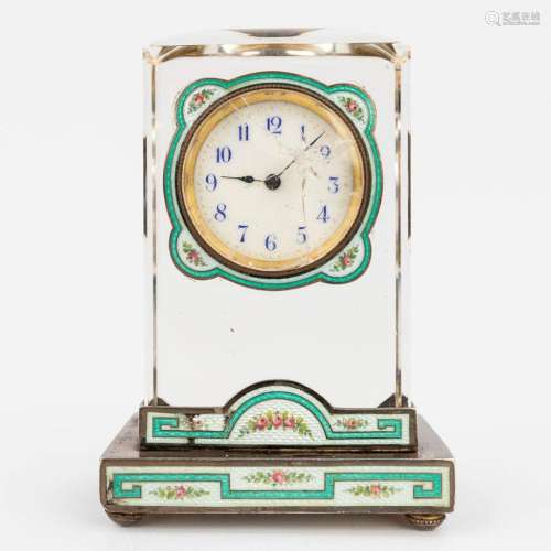 An antique table clock made of glass and finished with green...