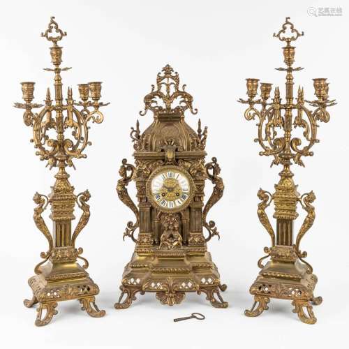 A three-piece mantle garniture clock and candelabra made of ...