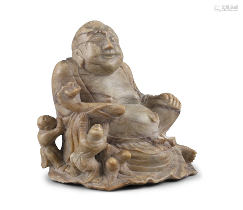 A SOAPSTONE CARVING OF A SEATED BUDAI WITH BOYS CHINA, CIRCA...