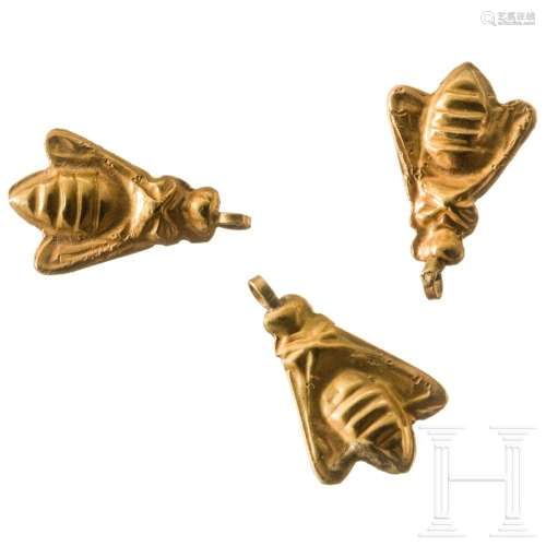 Three golden pendants in the shape of "bees". East...