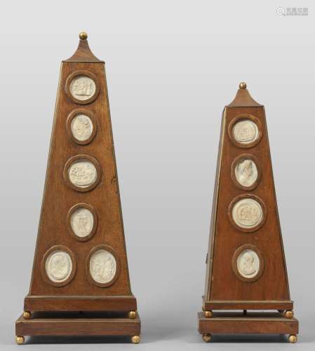 Due obelischi in legno con cammei in gesso,