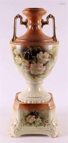 A pottery vase with handles, on a matching loose pedestal, e...
