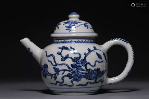 A blue and white teapot with wrapped branches and flowers fr...