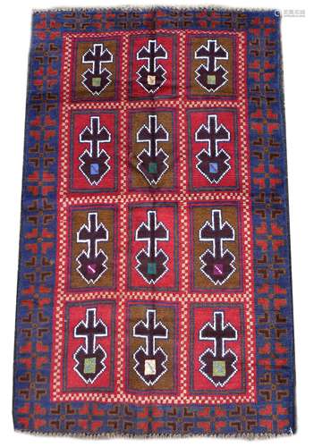 An old Baluchi rug, with red ground, twelve rectangular pane...