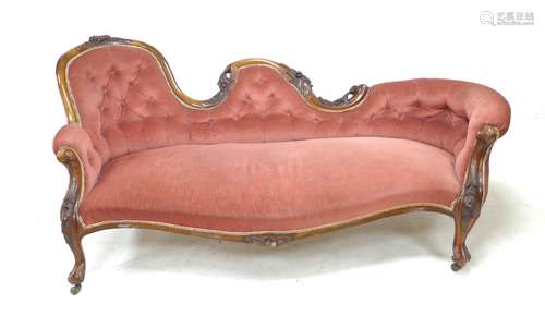 A Victorian walnut framed settee, covered in a pink button b...