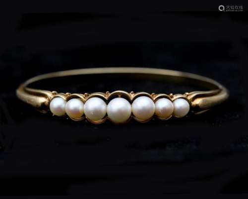 A 14 karat gold bangle with Akoya pearls