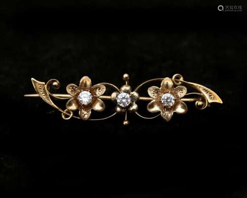 A 14 karat gold floral decorated brooch set with three cubic...
