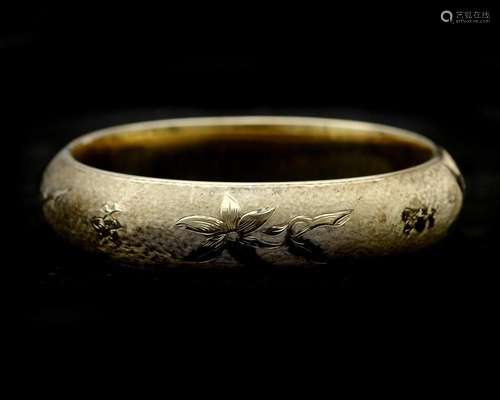 A 14 karat gold bangle with flower engraving