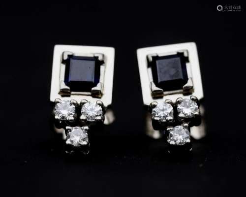 A pair of 14 karat white gold stud earrings, set with a blue...