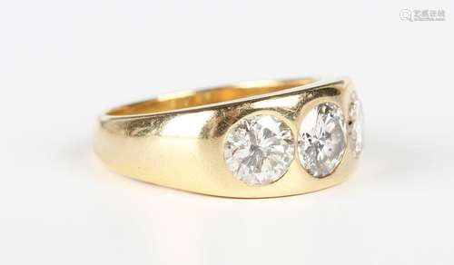 A gold and diamond three stone ring, gypsy set with a row of...