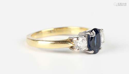 An 18ct gold ring, claw set with an oval cut sapphire betwee...