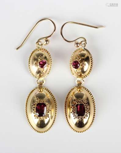 A pair of gold and garnet pendant earrings, each oval drop m...