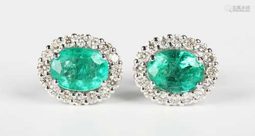 A pair of white gold, emerald and diamond oval cluster earst...