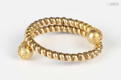 A gold circular sprung bangle, each terminal of spherical fo...