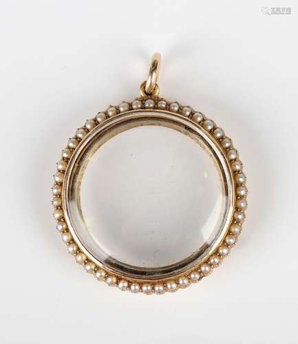 A gold and seed pearl circular pendant locket, glazed to the...