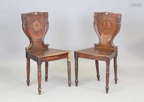 A pair of Regency mahogany hall chairs with carved backs and...