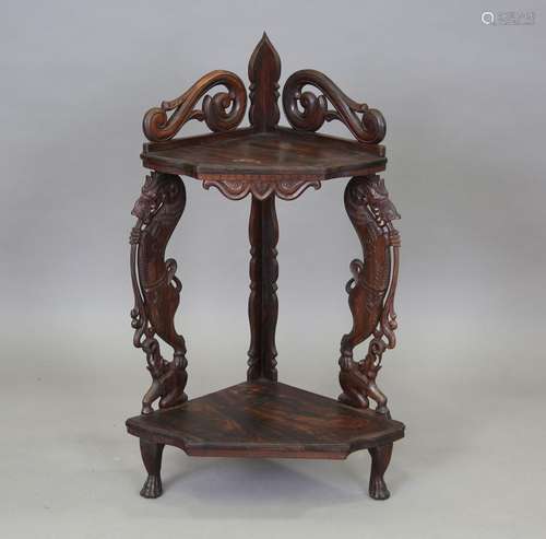 A 20th century Burmese hardwood two-tier corner shelf, the t...