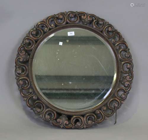 A George V oak circular wall mirror with a carved scroll fra...