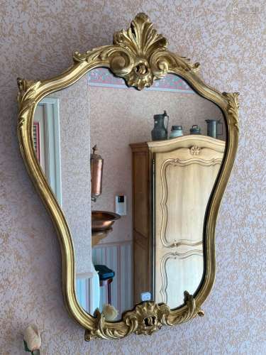 Un miroir de forme violonnée, en bois et stuc doré, surmonté...