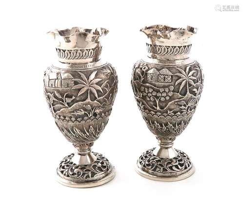 A pair of Indian silver vases, baluster form, chased village...