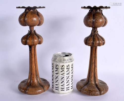 A PAIR OF ARTS AND CRAFTS CARVED WOOD CANDLESTICKS of scroll...