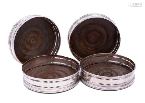 A set of four silver plated wine coasters: of circular outli...