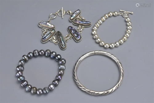 A GROUP OF FOUR SILVER AND PEARL BRACELETS AND BANGLE