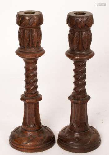 A pair of turned oak candlesticks with leaf and spiral desig...