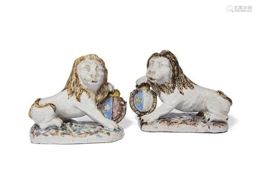 A pair of Continental faience armorial lion candlesticks