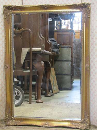 A contemporary mirror, moulded and swept gilded frame, bevel...