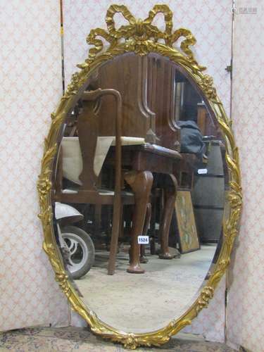 A decorative oval gilt framed mirror with ribboned and repea...