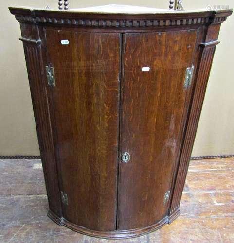 Georgian oak hanging corner cupboard of bow fronted outline,...