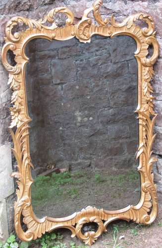 A gilded wall mirror in an 18th century style with floral an...