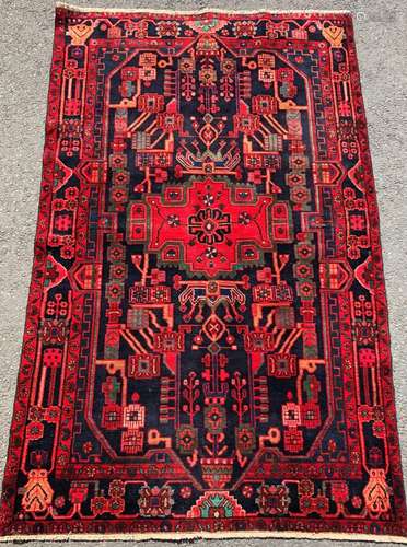 A Nahawand carpet brightly coloured with a central medallion...