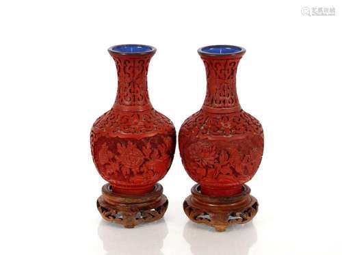 A pair of Chinese cinnabar lacquered vases, on wooden stands...