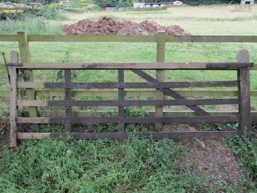 A stained and weathered softwood five bar field gate with ch...