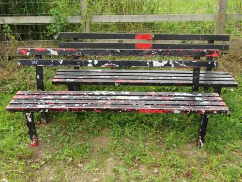 A pair of painted metal municipal/park benches with slatted ...