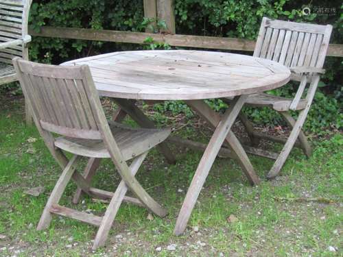 A weathered hardwood folding circular garden table with slat...