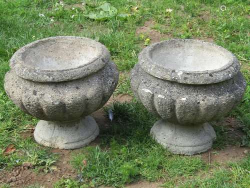 A pair of weathered cast composition stone garden urns, the ...