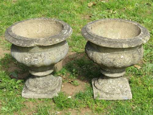 A pair of weathered cast composition stone garden urns, the ...