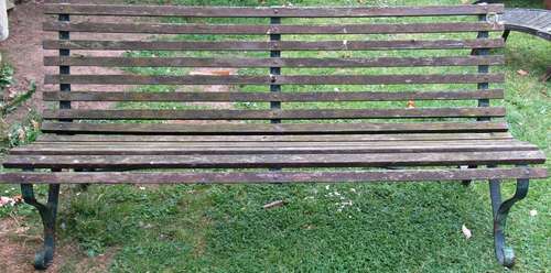 A vintage garden bench with weathered timber slatted seat an...