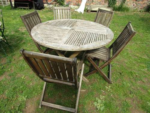 A weathered hardwood circular topped garden table with slatt...