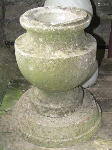 A small weathered marble urn raised on an associated stepped...