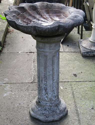 A weathered cast composition stone bird bath, the scallop sh...