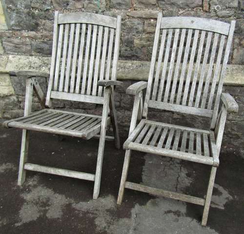 A pair of weathered hardwood folding garden armchairs with s...